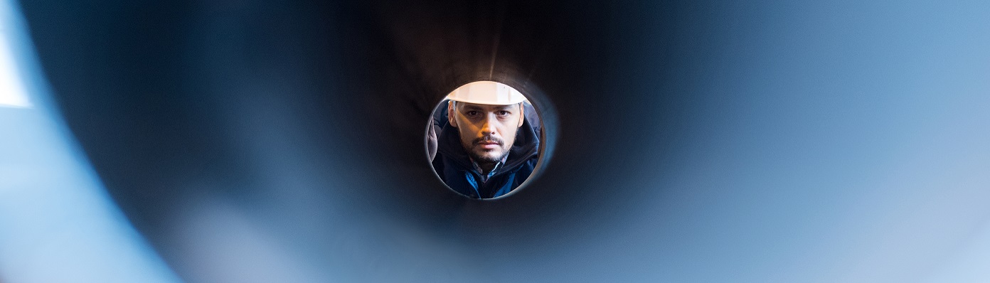 man looking through a pipe